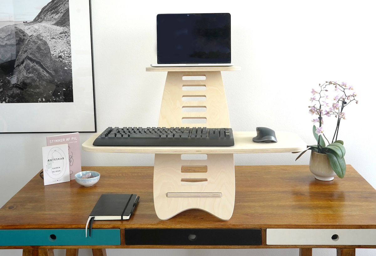 Gaia Craft hæve sænkebord i Birk, som står på et dekoreret skrivebord, med en computer, et tastatur og en mus placeret på hæve sænkebordet