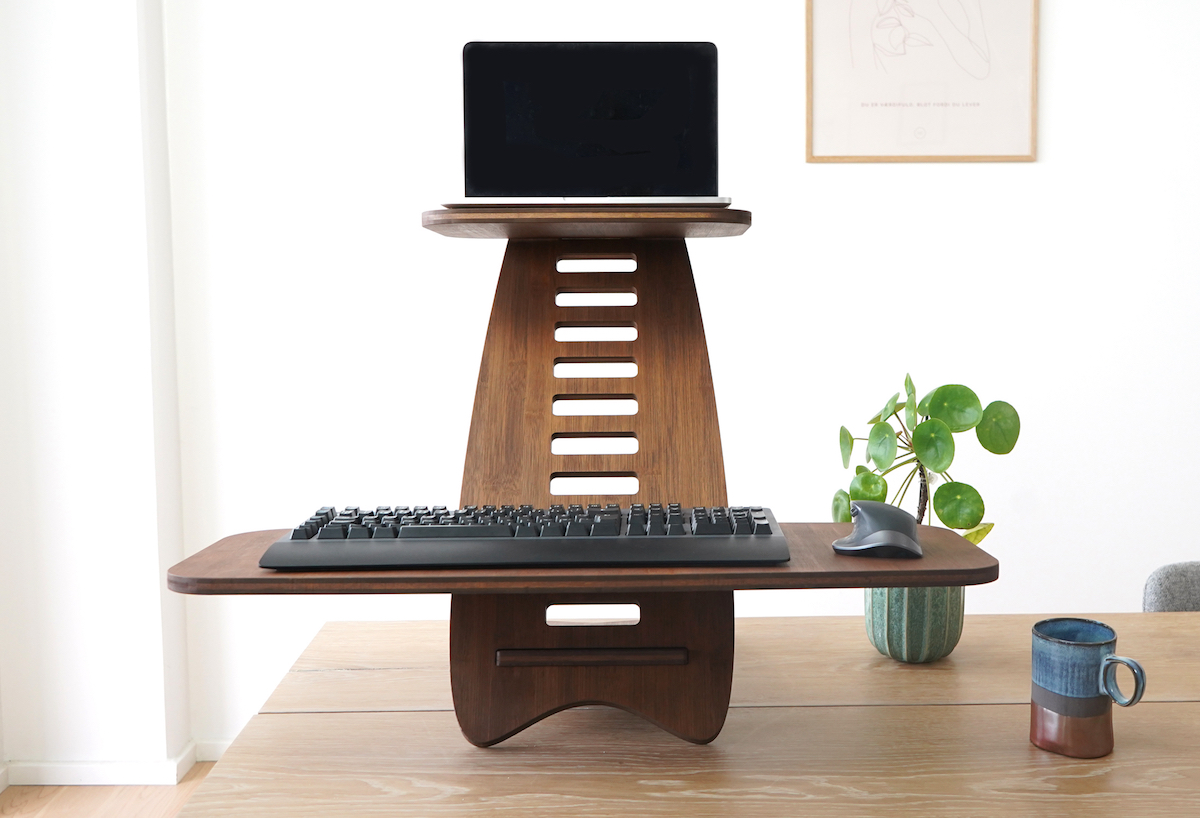 Gaia Craft hæve sænkebord i 'Mørk', som står på et skrivebord, med en computer, et tastatur og en mus placeret på hæve sænkebordet